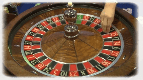 la mano de couprier lanzando la bola en la ruleta de casino
